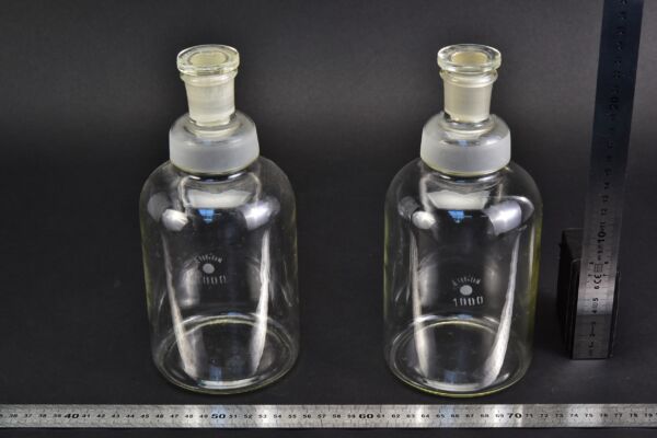 Pair of ERGON clear acid storage bottles with ground-glass stoppers, without protective caps Pair of ERGON clear acid storage bottles with ground-glass stoppers, without protective caps