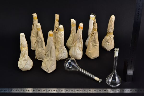 Set of thirteen volumetric flasks with glass stoppers, partly paper-wrapped, 100 ml Set of thirteen volumetric flasks with glass stoppers, partly paper-wrapped, 100 ml
