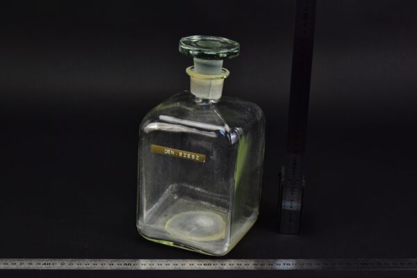 Square laboratory reagent bottle with glass stopper and “DEN. SZESZ” label