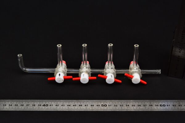 Four-stopcock laboratory glass manifold with red-and-white plugs Four-stopcock laboratory glass manifold with red-and-white plugs